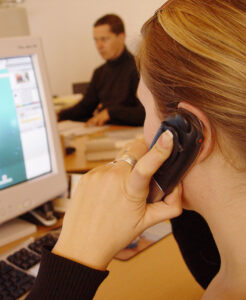 Woman lookinat computer screen talking on cell phone